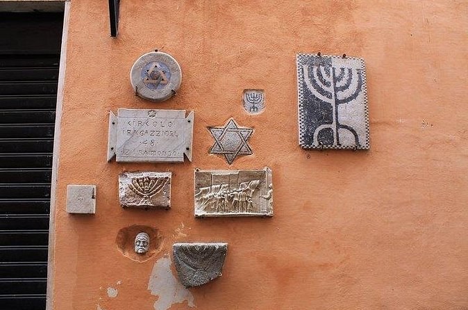 A menorah, a Star of David and carved plaques set into an ochre wall in the Jewish Ghetto