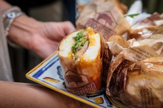 A filled sandwich handed over in its paper wrapper at a street-food stop