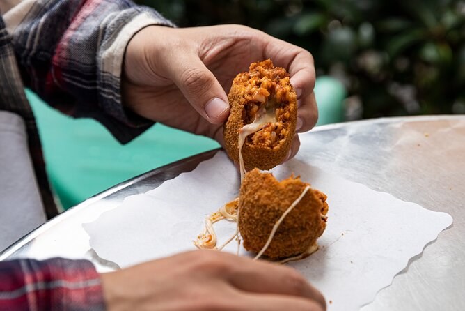 A supplì pulled open, the mozzarella stretching between the two halves